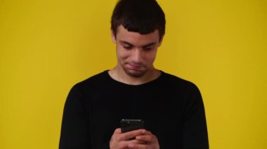Sarı arka planda telefonu kullanan bir adamın 4K videosu. Duygu kavramı.