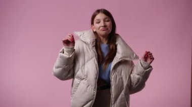 Pembe arka planda kurnaz yüz ifadesi olan bir kızın 4K videosu. Fikirleri olan kız kavramı.