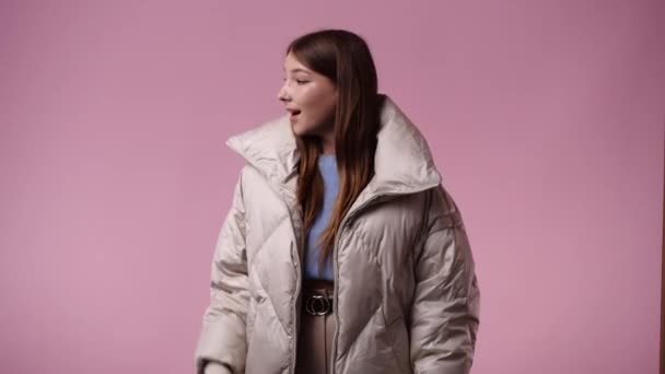 1人の女の子がピンクの背景の上に左を指している4Kビデオ 感情の概念 — ストック動画