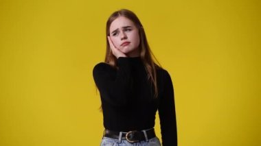 4k video of one girl with negative facial expression over yellow background. Concept of emotions.