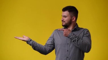 Sol tarafı işaret eden ve sarı arka planı gösteren 4K 'lık bir adam videosu. Duyguların kavramı.