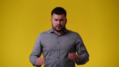 Sarı arka planda başı ağrıyan bir adamın 4K videosu. Duyguların kavramı.