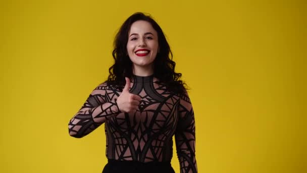1人の女の子の4K動画は興奮して黄色の背景に親指を表示します 感情の概念 — ストック動画