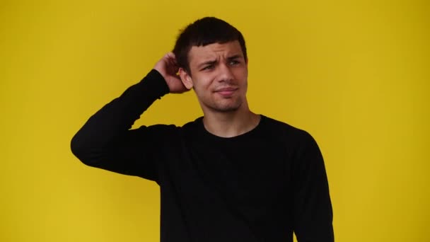 4K视频 一个男人在黄色背景下 脸上有深思熟虑的表情 有思想的人的概念 — 图库视频影像