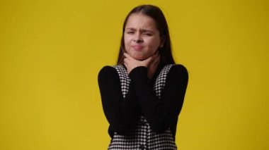 4k video of one girl with negative facial expression over yellow background. Concept of emotions.