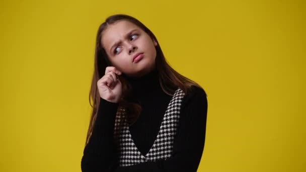 黄色い背景に思慮深い表情の女の子の4K動画 アイデアを持つ少女の概念 — ストック動画