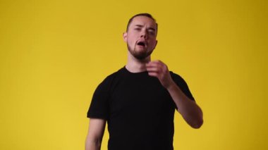 Bir adamın yudumladığı ve sarı arka planda uyandığı 4K video. Duyguların kavramı.
