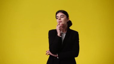 Bir kızın bir şeyler planladığını gösteren 4k 'lik video sarı arka planda yer alıyor. Duyguların kavramı.