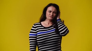 Sarı arka plandaki bir şeyden endişelenen bir kadının 4K videosu. Duyguların kavramı.