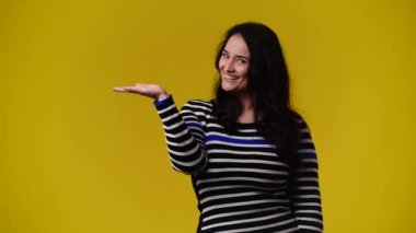 Sağ elinde sarı arka planda bir şeye işaret eden bir kadının 4K videosu. Duyguların kavramı.