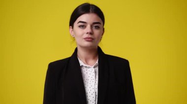 Sarı arka planda poz veren bir kızın 4K videosu. Duyguların kavramı.