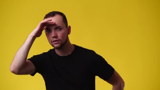 1人の男の4Kビデオ誰かを探して黄色の背景にこんにちはと言って 感情の概念 — ストック動画