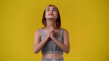 Sarı arka planda poz veren bir kızın 4K videosu. Duyguların kavramı.