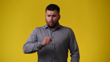 Sarı arka planda öksüren bir adamın 4K videosu. Duygu kavramı..