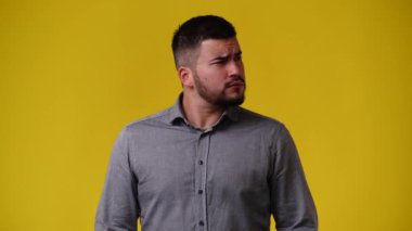 Sarı arka planda düşünceli yüz ifadesi olan bir adamın 4K videosu. Fikirleri olan insan kavramı.