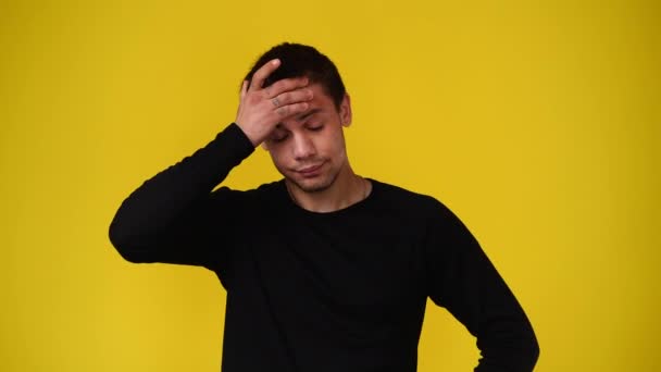 黄色の背景の上に頭痛のある男の4Kビデオ 感情の概念 — ストック動画