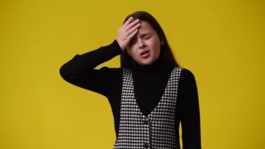 Sarı arka planda düşünceli yüz ifadesi olan bir kızın 4K videosu. Fikirleri olan kız kavramı.