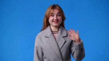 Mavi arka planda gülümseyen bir kızın 4K videosu. Duyguların kavramı.
