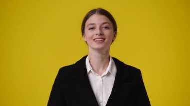 Sarı arka planda kurnaz yüz ifadesi olan bir kızın 4K videosu. Fikirleri olan kız kavramı.