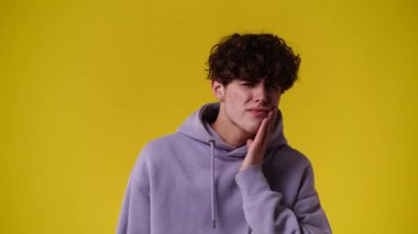 Sarı arka planda negatif yüz ifadesi olan bir adamın 4K videosu. Olumsuz duygu kavramı.