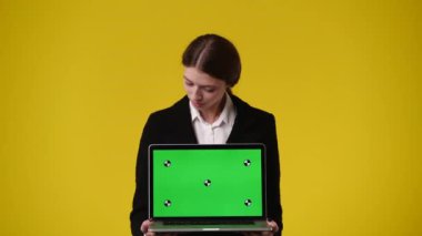 Krom anahtar dizüstü bilgisayar kullanan ve sarı arka planda gülümseyen bir kızın 4K videosu. Duygu kavramı..