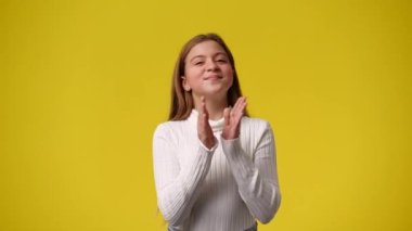 Sarı arka planda poz veren bir kızın 4K videosu. Duyguların kavramı.