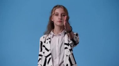 Mavi arka planda poz veren bir kızın 4K videosu. Duyguların kavramı.