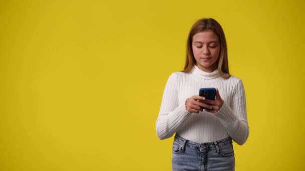Video Jedné Dívky Ukazuje Vlevo Pomocí Telefonu Žlutém Pozadí Koncept — Stock video