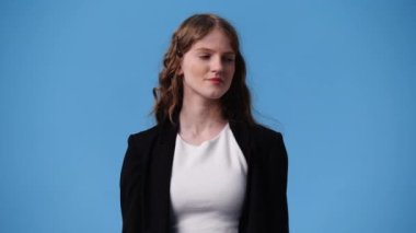 Mavi arka planda poz veren bir kızın 4K videosu. Duyguların kavramı.