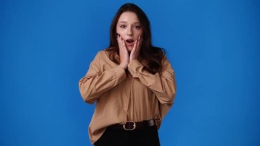 Mavi arka planda gülümseyen güzel bir kızın 4K videosu. Duyguların kavramı.