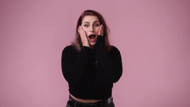 ピンクの背景の上にビデオをポーズしている1人の女の子の4Kビデオ 感情の概念 — ストック動画