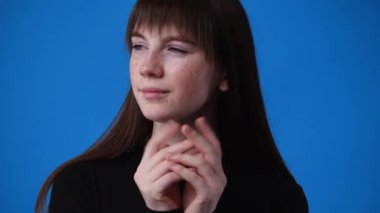 Bir kızın mavi arka planda bir şeyler düşündüğü 4K video. Duyguların kavramı.