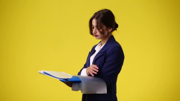 黄色の背景の紙で何かを考えている1人の女の子の4Kビデオ 感情の概念 — ストック動画