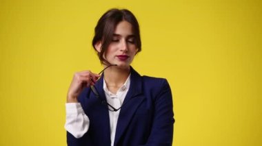 Sarı arka planda poz veren bir kızın 4K videosu. Duyguların kavramı.