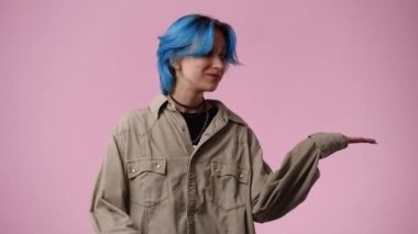 Mavi saçlı bir kızın 4K videosu sağı gösteriyor ve pembe arkaplanı gösteriyor. Duygu anlayışı..