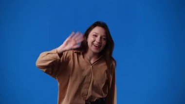 Mavi arka planda poz veren bir kızın 4K videosu. Duyguların kavramı.