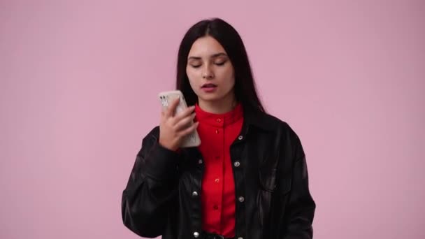 Video Von Einem Mädchen Das Ihr Handy Über Rosa Hintergrund — Stockvideo