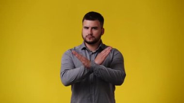Sarı arka planda negatif yüz ifadesi olan birini durduran bir adamın 4K yavaş çekim videosu. Duyguların kavramı.