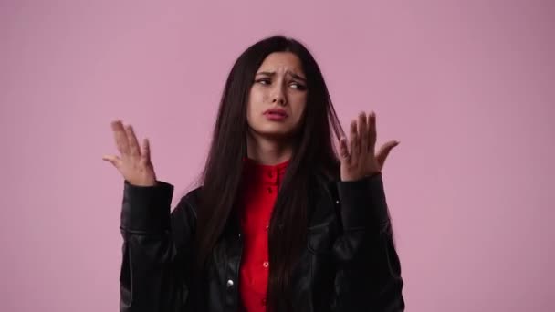 ピンクの背景の上に彼女の手で自分自身を冷却しようとする1人の女の子の4Kビデオ 感情の概念 — ストック動画