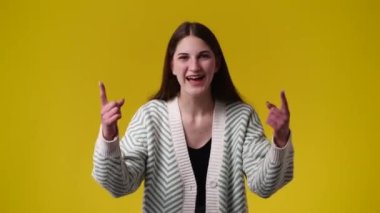 4k video of one girl showing thumbs up over yellow background. Concept of emotions.