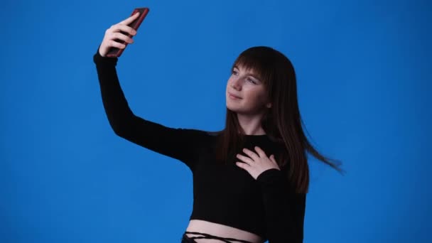 Video Una Chica Que Toma Selfies Teléfono Sobre Fondo Azul — Vídeo de stock