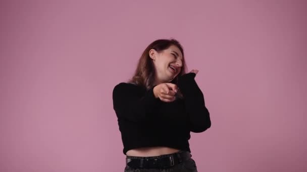 誰かを指差してピンクの背景を笑っている1人の女の4K動画 感情の概念 — ストック動画