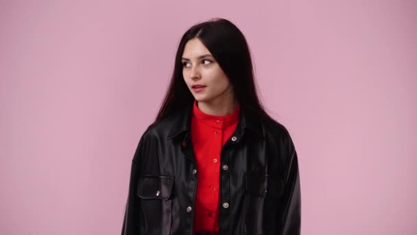 一个女孩的4K视频环视四周 在粉色背景上显示沉默的标志 情绪的概念 — 图库视频影像