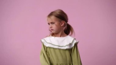 Pembe arka planda negatif tepki veren bir çocuğun 4k videosu. Duyguların kavramı.