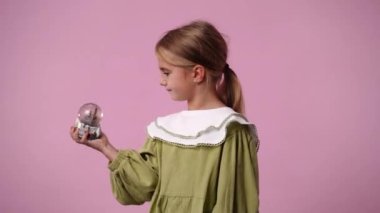 Pembe arka planda bir oyuncakla oynayan bir çocuğun 4K videosu. Duyguların kavramı.