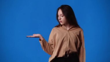 Sağ elinde mavi arka planda bir şey gösteren bir kızın 4K videosu. Duyguların kavramı.