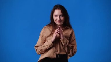 Mavi arka planda bir şey olan bir kızın 4K videosu. Duyguların kavramı.