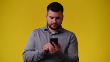 Sarı arka planda gülümseyen ve yazı yazan bir adamın 4K videosu. Duyguların kavramı.