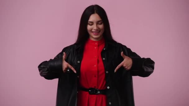 ピンクの背景を指差している1人の女の子の4Kビデオ 感情の概念 — ストック動画