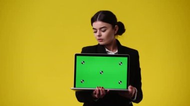 Bir kızın krom anahtar dizüstü bilgisayarı kullanırken ve sarı arkaplan üzerinde başparmak gösterirken 4K videosu. Duygu anlayışı..